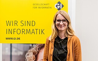 Portraitfoto von Anna Lieckfeld vor GI-Hintergrund mit Text "Wir sind Informatik"
