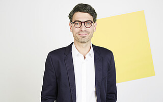 Portraitfoto von Nikolas Becker im Anzug vor hellem Hintergrund